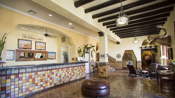 A lobby with a tiled reception desk, a large wooden bench, and a staircase leading to upper floors.