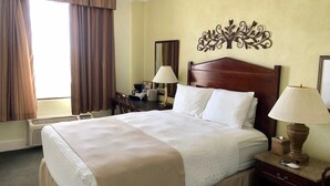 Une chambre d’hôtel avec un grand lit, un bureau avec une chaise, une lampe de bureau et un élément décoratif mural.