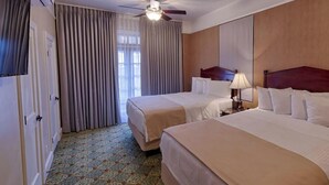 Une chambre d’hôtel avec deux lits, un ventilateur de plafond, une lampe et une fenêtre avec des rideaux.