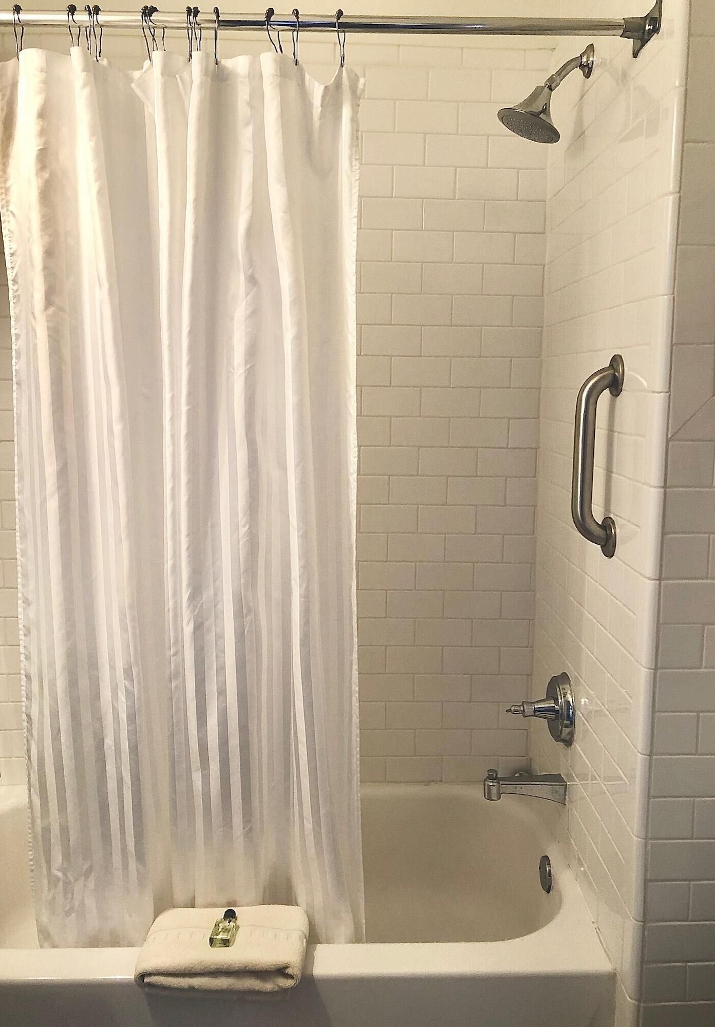 A bathroom with a bathtub, a shower, and a curtain.