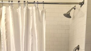 Une salle de bain avec une baignoire, une douche et un rideau.
