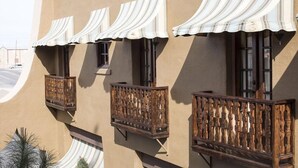 Un edificio con varios balcones, cada uno con barandilla de madera y toldo blanco.