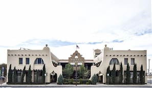 A hotel with a distinctive architectural design, featuring a central entrance with a flag, and symmetrical wings. - Hotel EL Capitan (Van Horn)