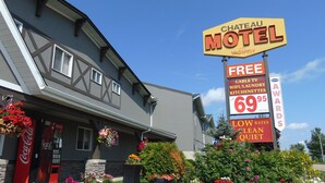 Chateau Motel mit einem großen Schild, das kostenlose Annehmlichkeiten wie Kabelfernsehen, WLAN, Wäscheservice und Küchenzeilen bewirbt.
