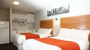 Ein Hotelzimmer mit zwei Betten, einer Küchenzeile und einem Stadtbild an der Wand.
