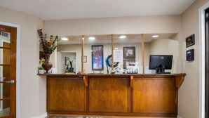 Un área de recepción con un mostrador de madera, una alfombra floral y cuadros en la pared.