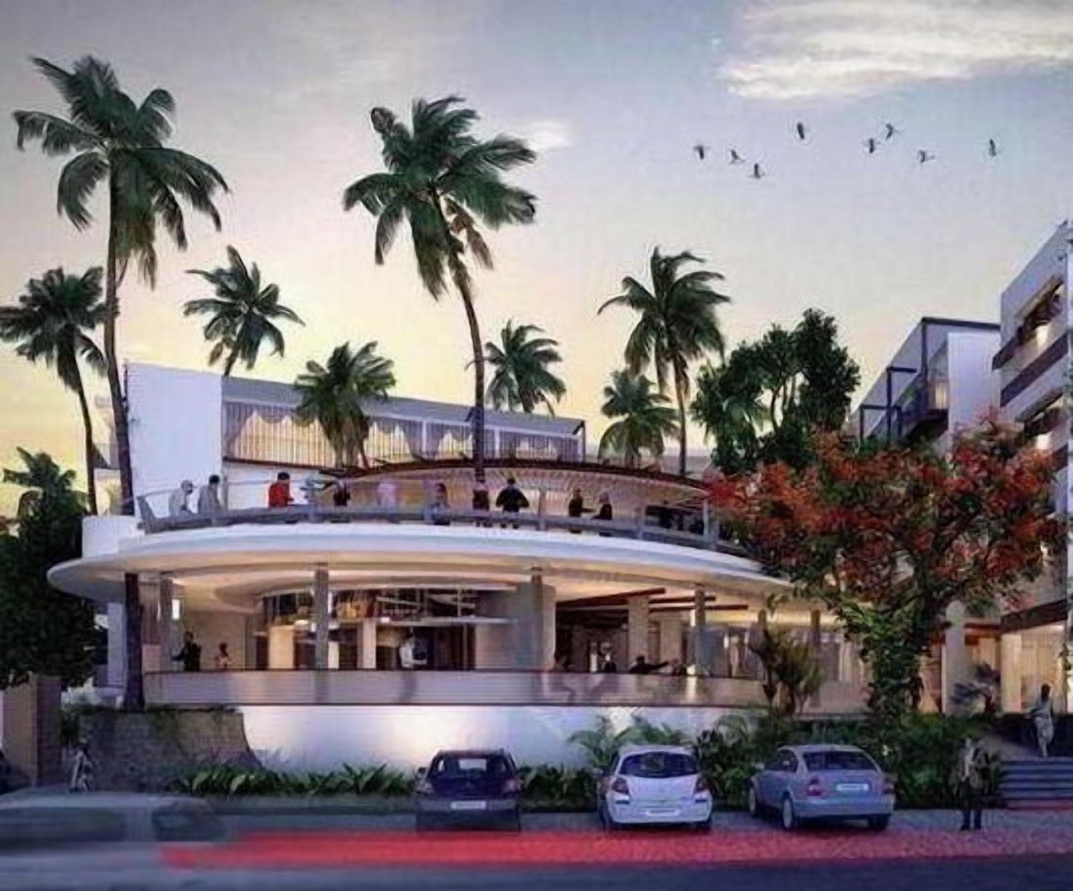 A modern hotel with a curved structure, palm trees, and a pool area.