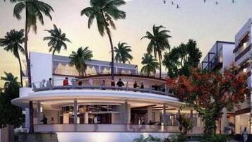A modern hotel with a curved structure, palm trees, and a pool area.