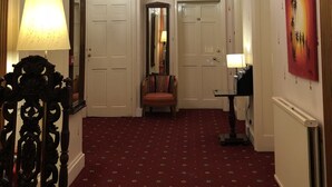 A hallway with a red carpet, white doors, a chandelier, and a mirror. - Atlas Guest House (Edinburgh)