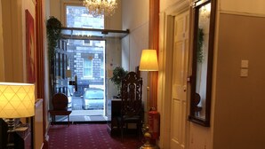A hotel hallway with a red carpet, a chandelier, and a view of the street outside. - Atlas Guest House (Edinburgh)