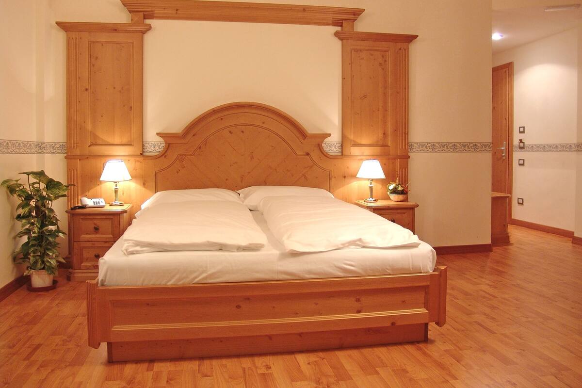Una cama con dosel de madera con dos mesitas de noche, cada una con una lámpara y un teléfono.