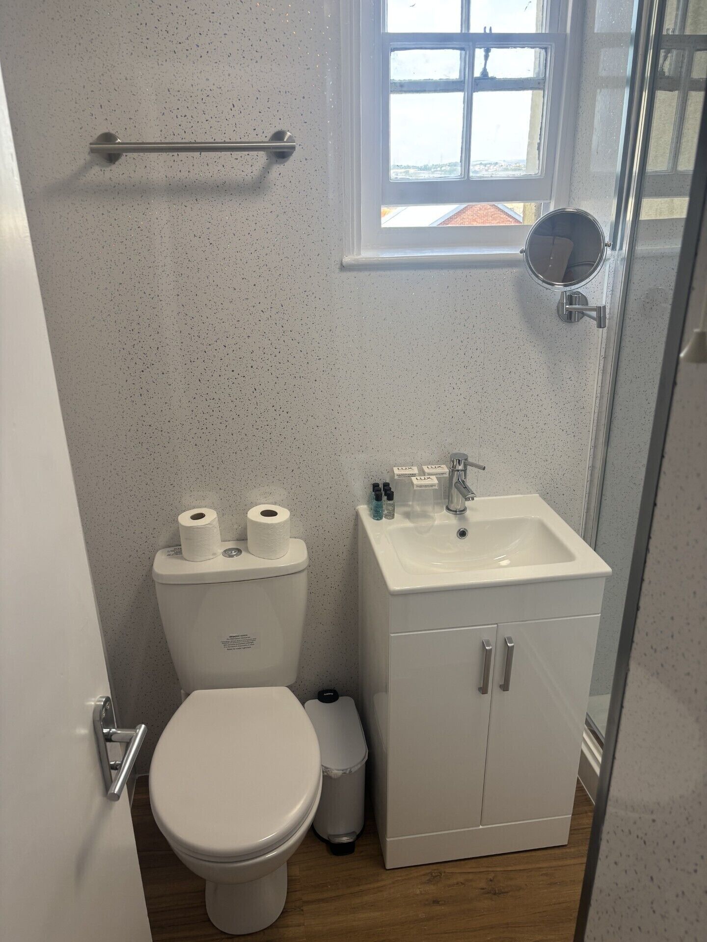 Un baño pequeño con inodoro, lavamanos y una ventana.