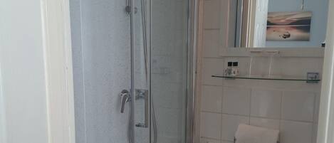 A bathroom with a glass-enclosed shower, a white sink, and a mirror above the sink.