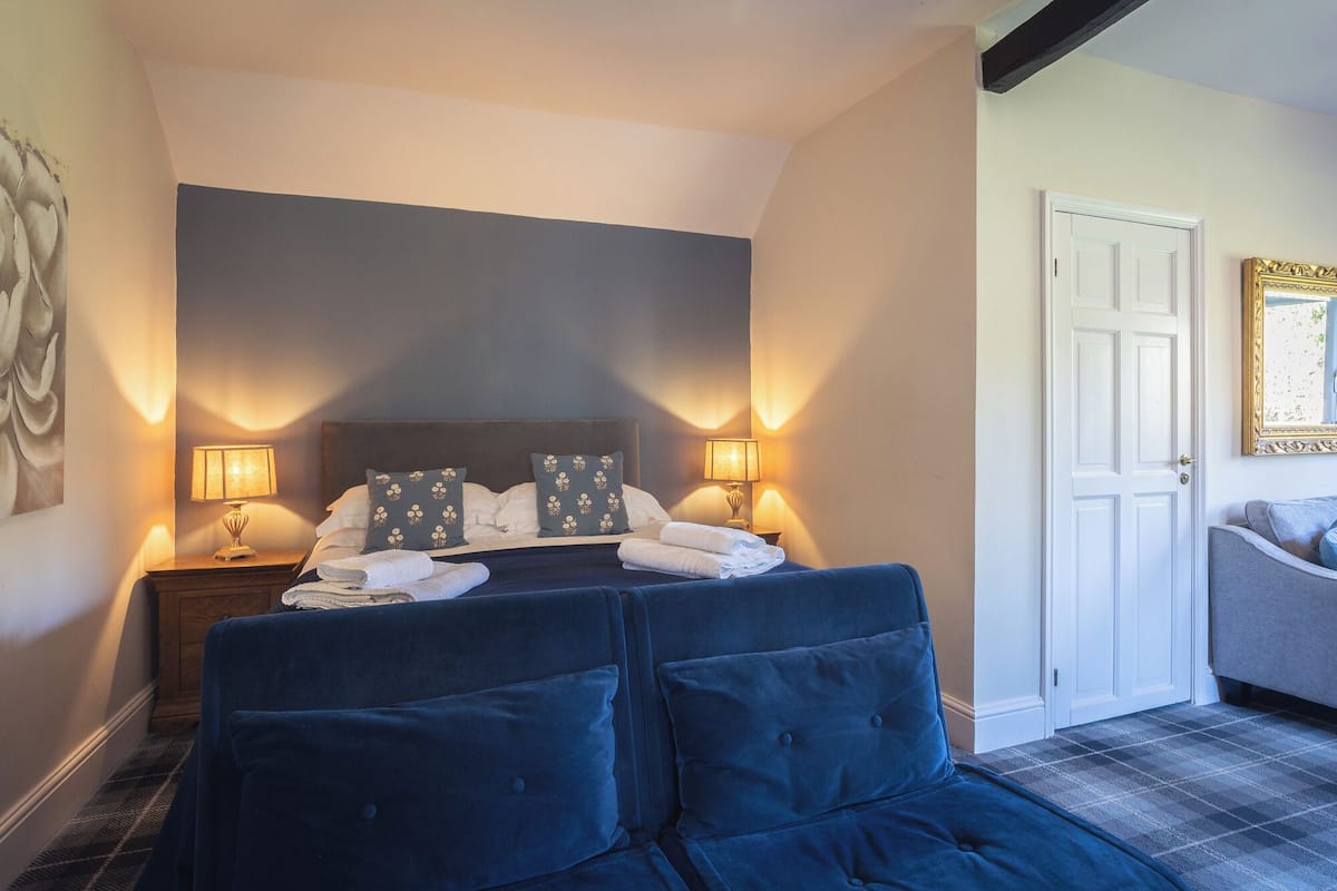 A bedroom with a large bed, two bedside lamps, a door, and a mirror.