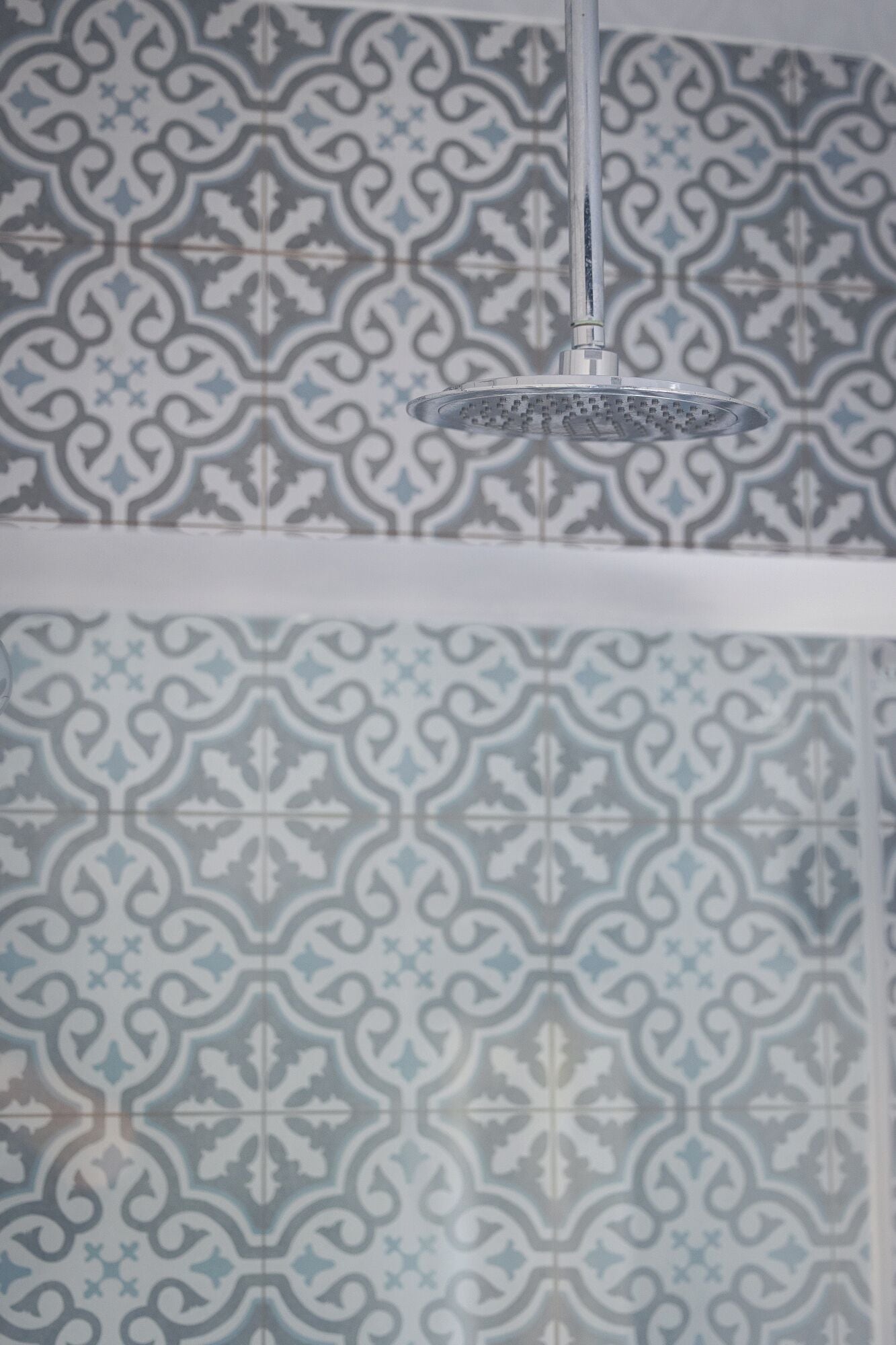 Ducha de diseño moderno frente a un muro con estampado.