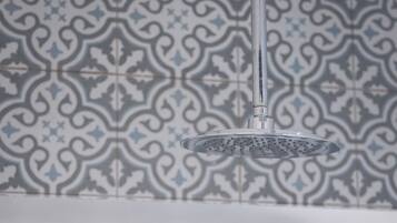 Ducha de diseño moderno frente a un muro con estampado.