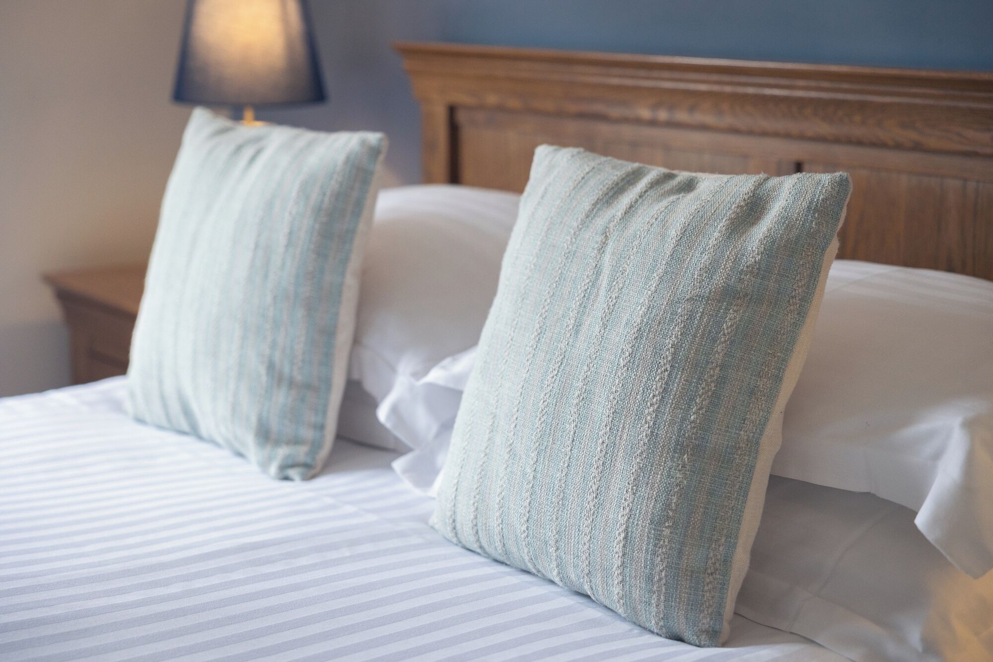 A neatly made bed with striped bedding and two pillows.