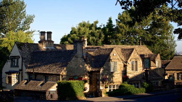 A traditional stone building with multiple chimneys, a central door, and flower boxes. - The Lamb Inn Great Rissington (Cheltenham)