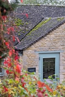 A stone building with a moss-covered roof and a sign reading "WITNEY".