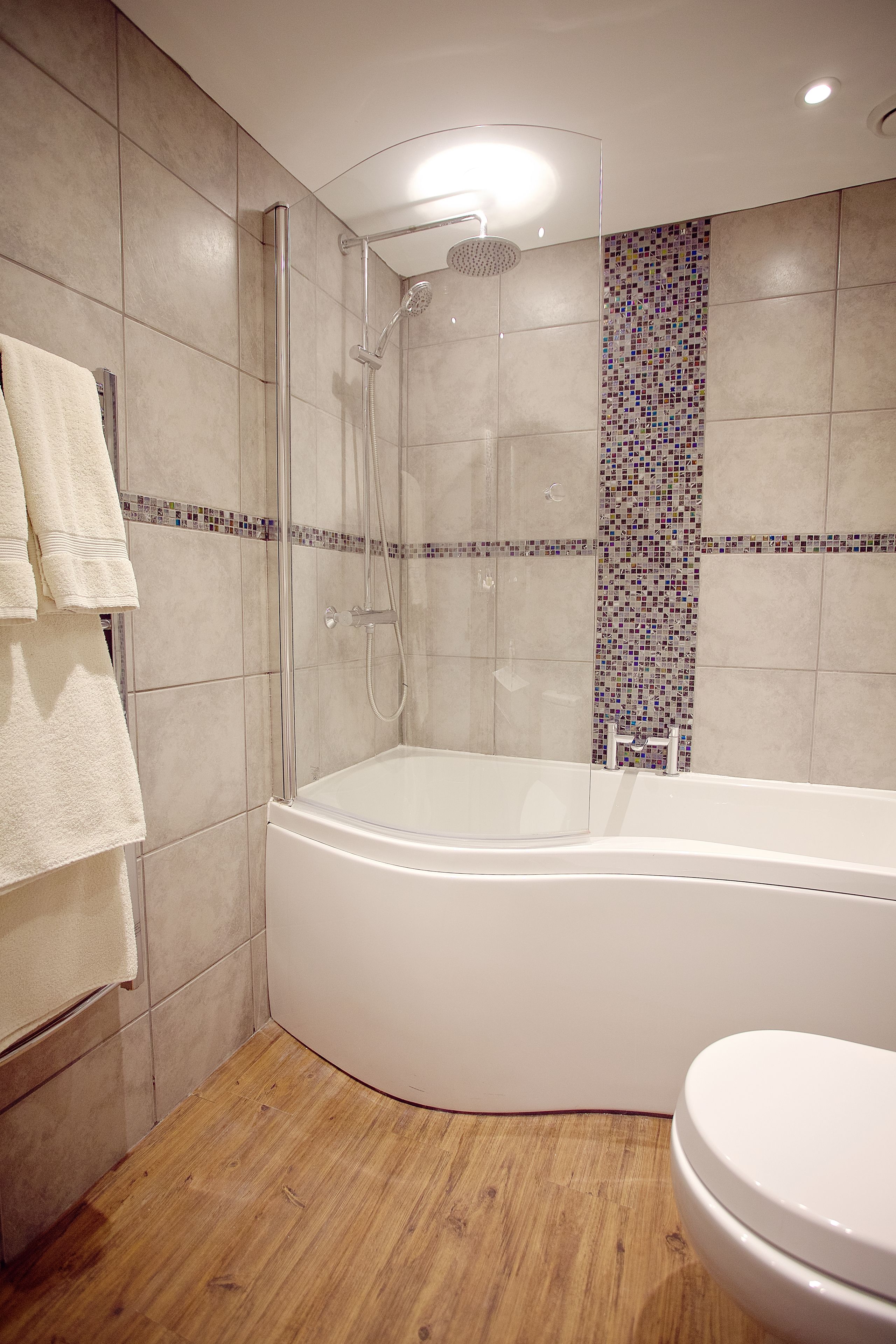 A modern bathroom with a glass-enclosed shower, a freestanding bathtub, and a toilet.