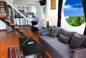Un salon moderne avec un canapé, une table basse et une vue dégagée sur l’extérieur grâce à une grande fenêtre.