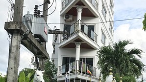 Un edificio con un letrero que dice 'Orchid Kathy Heights', que presenta una estatua de un caballo blanco, un cartel y un balcón con barandillas.