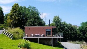 A modern two-story house with a balcony, surrounded by lush greenery and a clear sky. - Lobhill Farmhouse (Okehampton)