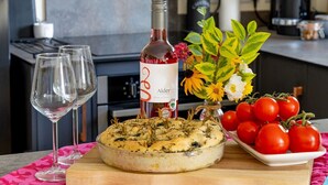 A kitchen counter with a pizza, a bottle of wine, a vase with flowers, and a plate of tomatoes. - Lobhill Farmhouse (Okehampton)