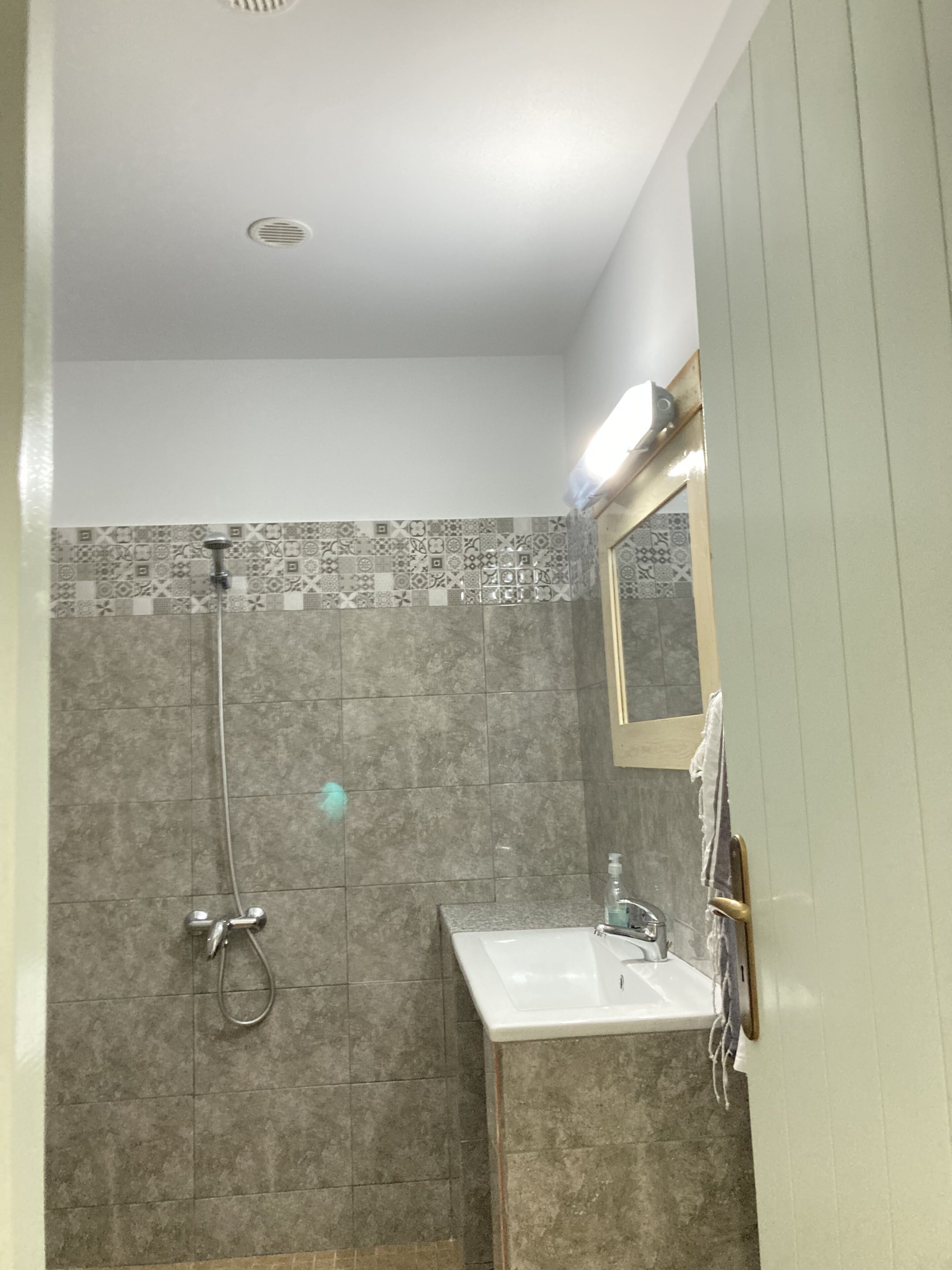 A bathroom with a shower, sink, and a mirror.