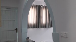 A room with a bed under an arched window, a door, and a tiled floor. - Hotel Le Beau Sejour (Mezraia)