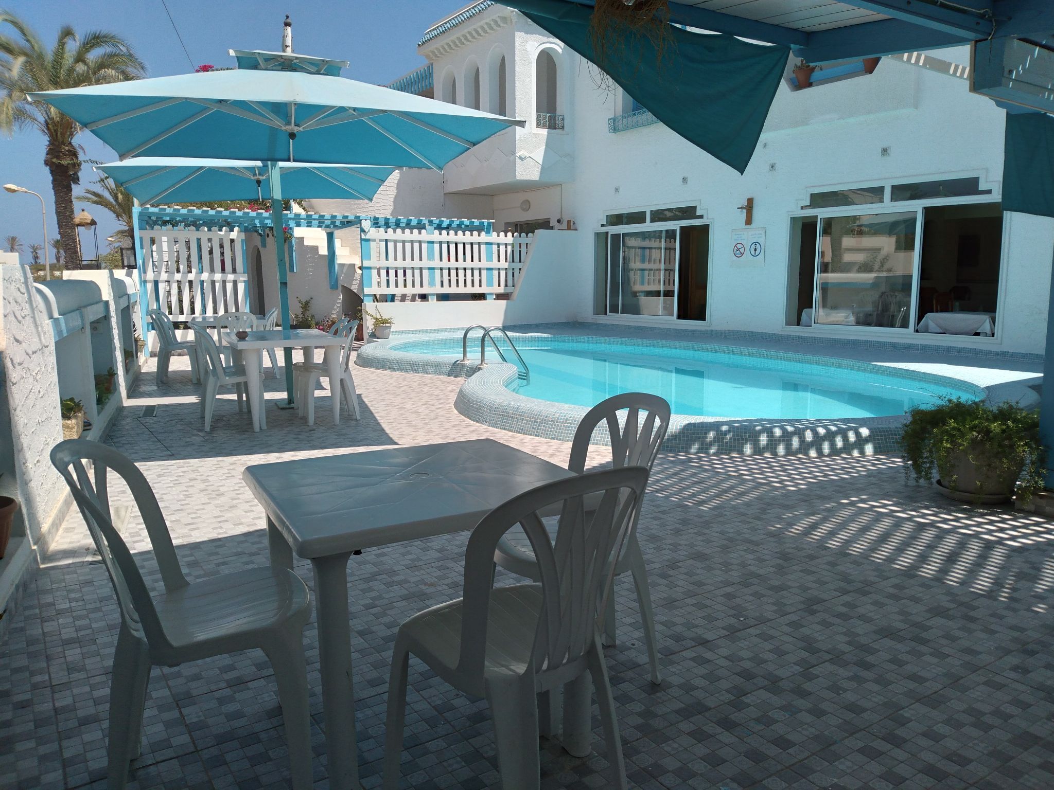 Un espace aménagé au bord de la piscine, comprenant une piscine, des sièges extérieurs et un patio couvert.