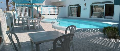 Un espace aménagé au bord de la piscine, comprenant une piscine, des sièges extérieurs et un patio couvert.