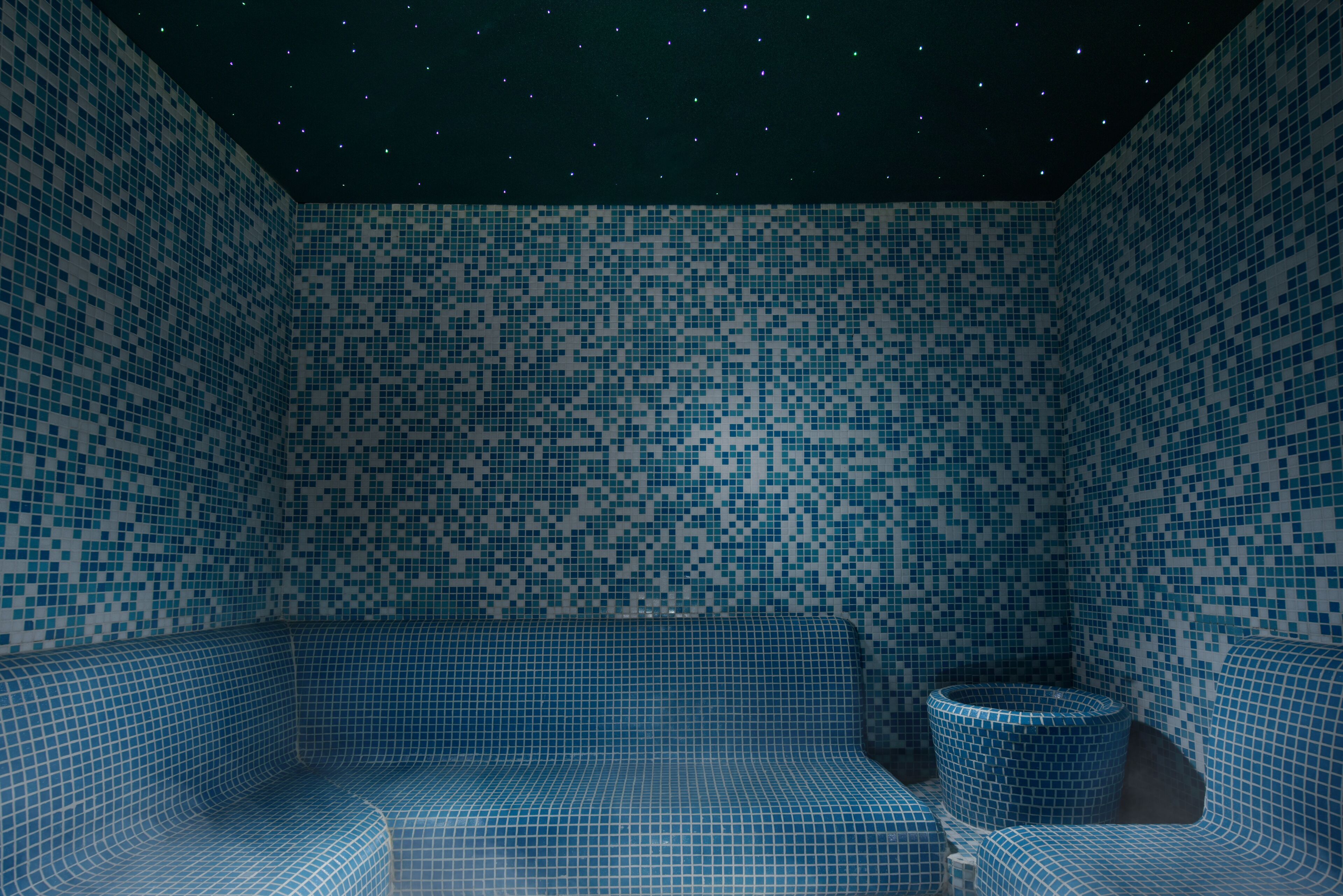 A room with a mosaic tile wall and a seating area.