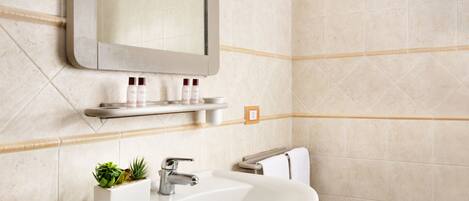 Une salle de bain avec un lavabo blanc, un miroir et une étagère contenant des articles de toilette.