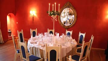 A dining room with a round table set for six, surrounded by six chairs with blue cushions.