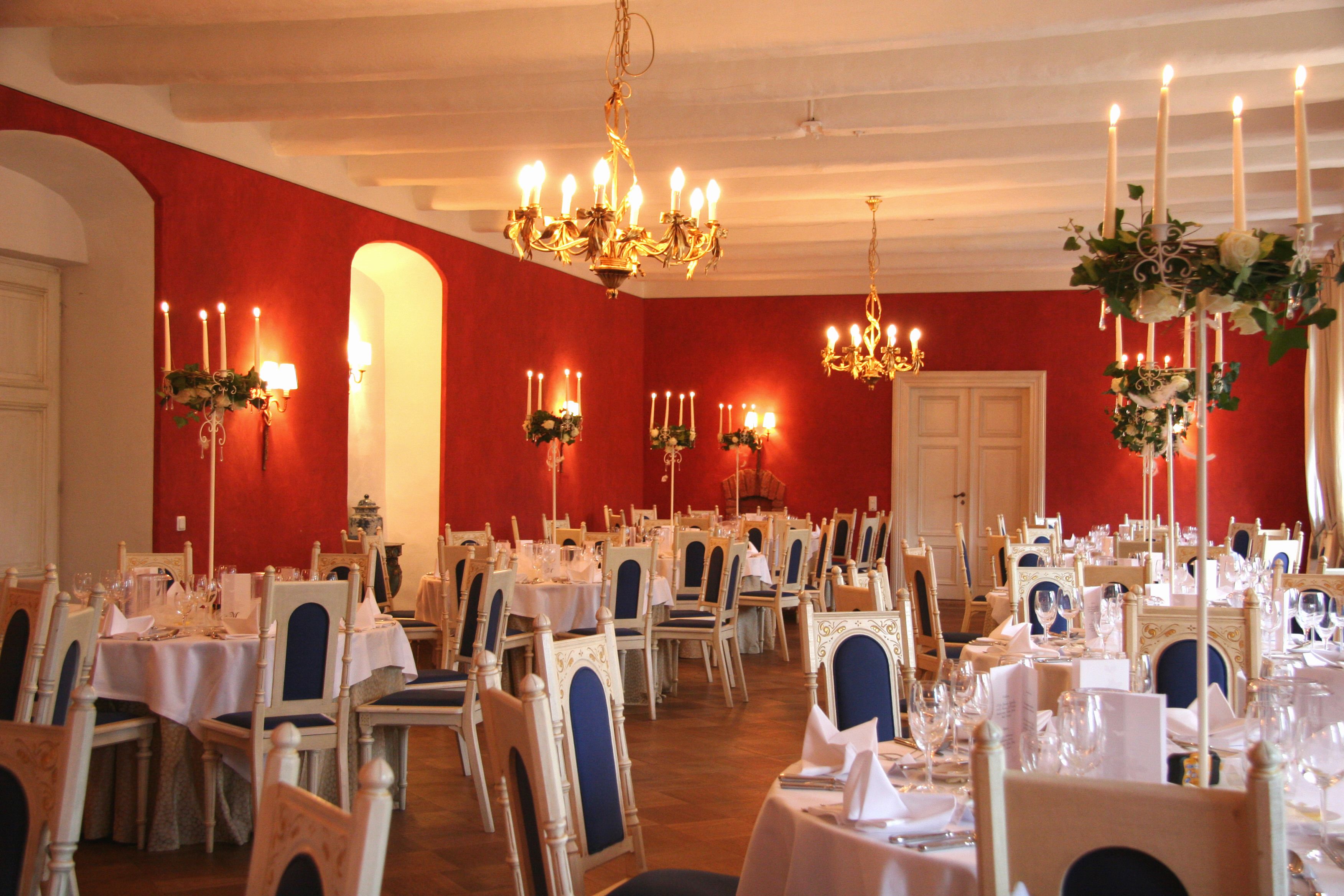 A banquet hall with multiple round tables set for dining, each with chairs and table settings.