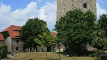 A stone tower with a red roof, surrounded by potted plants and a cobblestone courtyard.