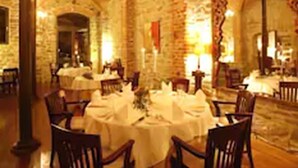 A dining area with round tables and chairs, brick walls, and a vaulted ceiling. - Hotel Burg Wanzleben (Wanzleben-Börde)