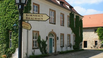 Ein Gebäude mit einem Kopfsteinpflasterhof, einer grünen Tür und Schildern, die zum Kornhaus und zum Roten Saal weisen.
