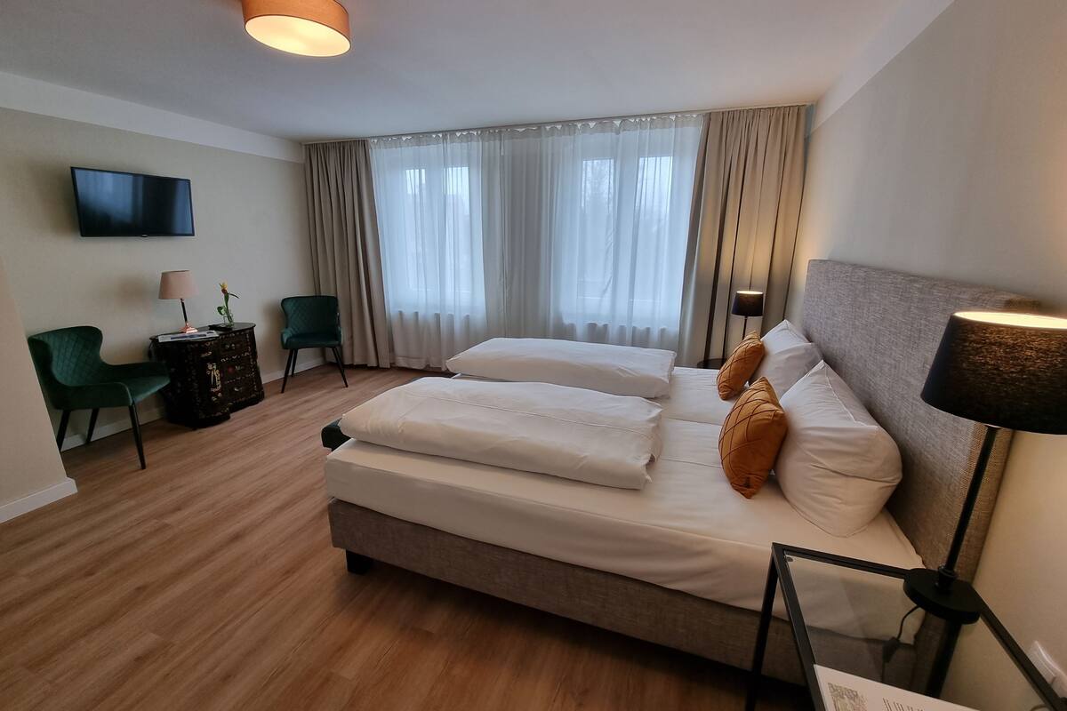 Una habitación de hotel con cama, escritorio, silla, televisor y lámpara.