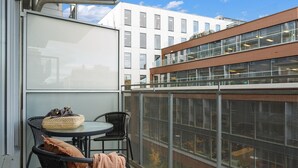 A balcony with a round table and two chairs, a wicker basket, and a brown cushion. - BJØRVIKA APARTMENTS, Teaterplassen, Oslo city center (Oslo)