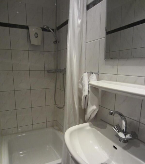 A bathroom with a shower, a sink, and a mirror.