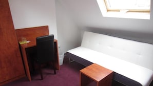 Ein kleiner Raum mit einem weißen Sofa, einem Holztisch, einem Stuhl und einem kleinen Tisch.