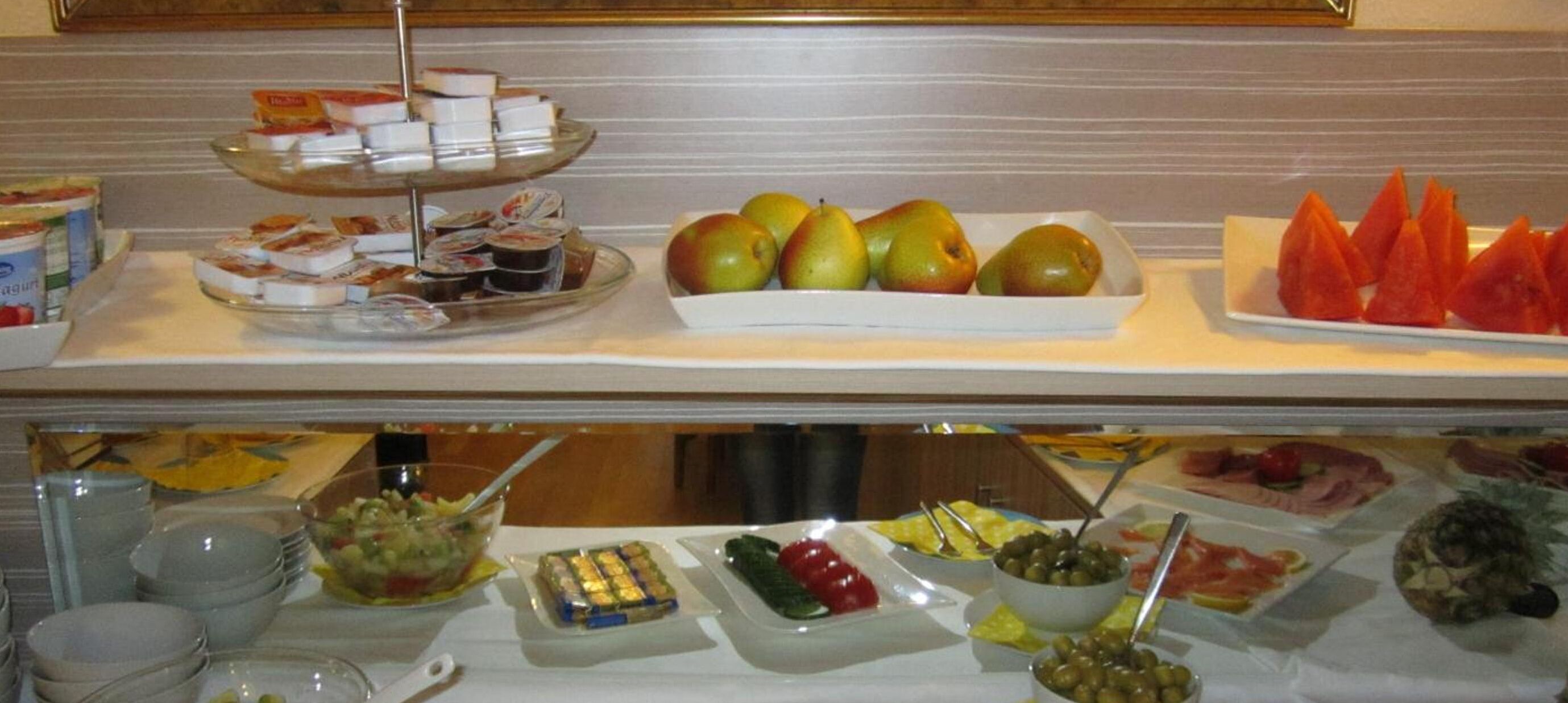 A buffet with various food items including fruits, cheeses, and salads.