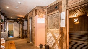 A wooden interior with a stone wall, a wooden bench, and a glass door leading to a room. - Al Posta Hotel 1899 (Baselga di Pine)