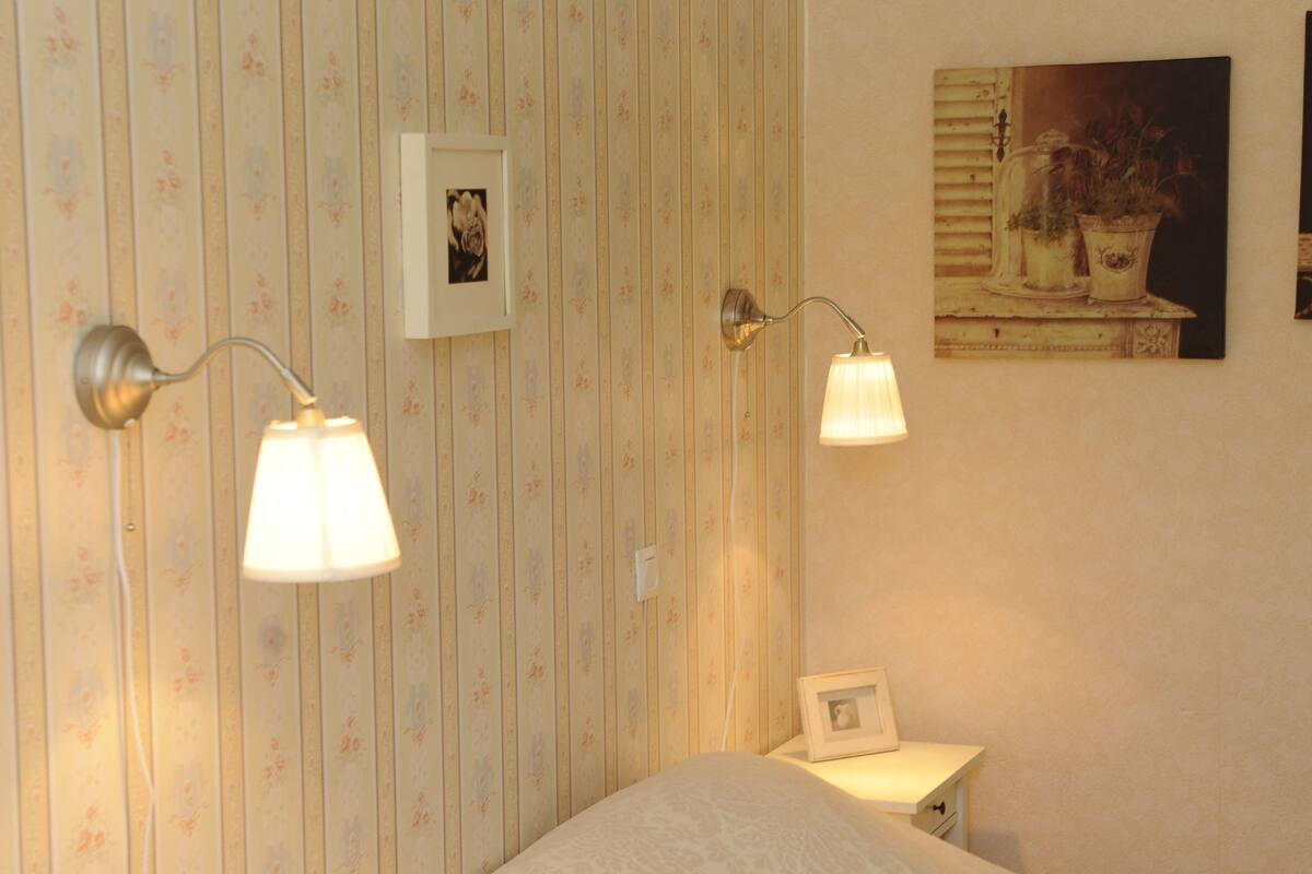 Un dormitorio con dos camas, una mesita de noche con lámpara y un cuadro enmarcado en la pared.
