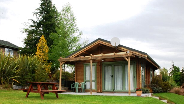 Une cabane en bois dotée d’un porche couvert, d’une table de pique-nique et de deux chaises.