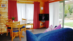 L’intérieur d’un chalet en bois comprend une table à manger, des chaises, un téléviseur et un canapé bleu.