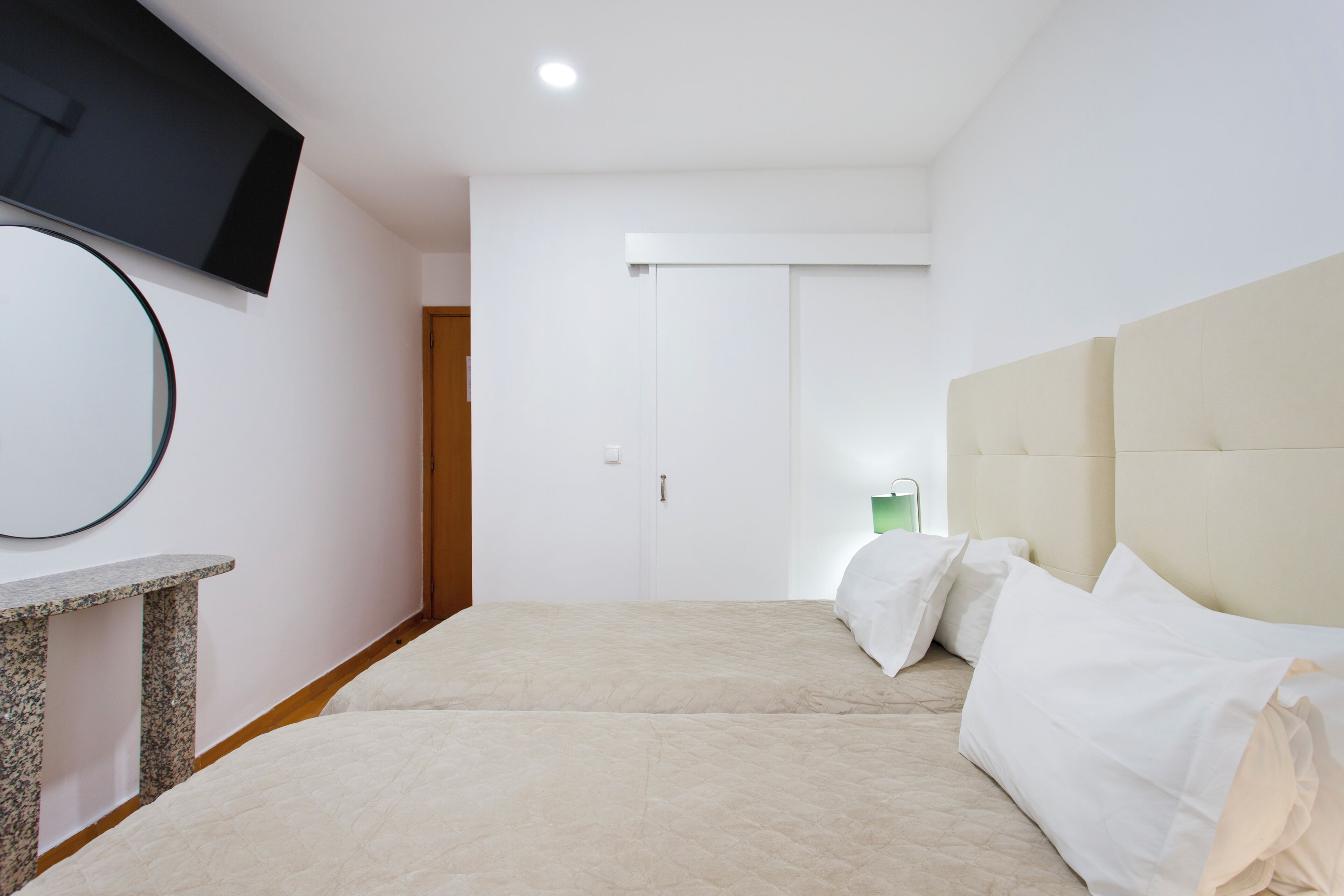 A bedroom with a bed, a television, a mirror, and a door.