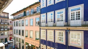 Un edificio de varios pisos con balcones, locales comerciales y vista a la calle.